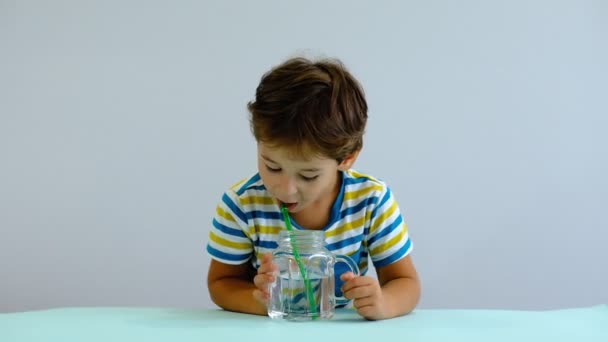 Câmera lenta asiático bonito criança bebendo água na cozinha. menino alegre gosta de soprar bolhas — Vídeo de Stock