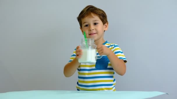 pomalý pohyb asijský roztomilá holčička pije mléko v kuchyni. Veselý hoch rád pije mléčný koktejl