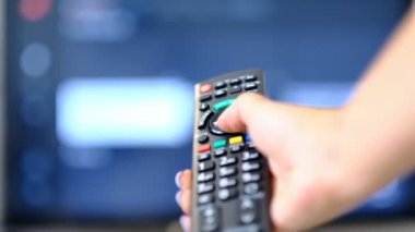 yavaş çekim kadın Tv izler ve uzaktan kumanda üzerinde bir düğmeye basar. el Tv uzaktan kumandatutarak ve akıllı tv kapatın. Kanal sörfü. bulanık arka plan