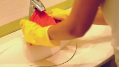 yavaş çekim. Evde banyoda ev işleri yapan kadın, sprey deterjanile lavabo ve musluk temizliği yapıyor. Kırpılmış görünüm