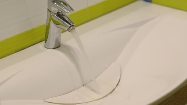 Slow motion. Water running from a tap into a sink. Close-up shot — Stock Video