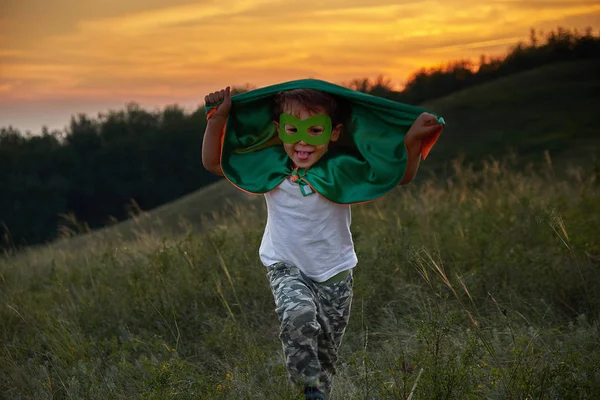 little boy playing a superhero. Kid in an Superheros costume. happy child runs to meet the photographer.