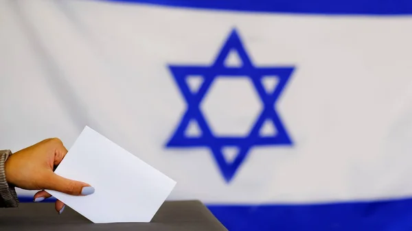 Hand holding ballot paper for election vote concept. elections, The hand of woman putting her vote in the ballot box. Israeli Flag on background. — Stock Photo, Image