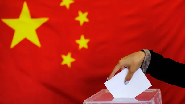 Hand holding ballot paper for election vote concept. elections, The hand of woman putting her vote in the ballot box. China Flag on background.