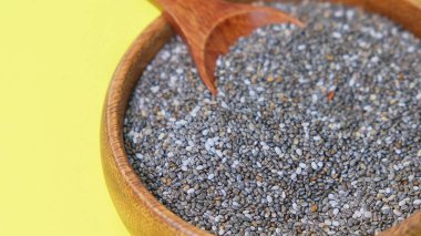 Sarı bir arka plan üzerinde besleyici chia tohumları. kase chia tohumları ve mutfak masası üst görünümünde bir kaşık. Sağlıklı ve diyet superfood ürün.