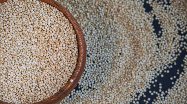 Siyah bir arka plan üzerinde beyaz Quinoa tohumları. Mutfak masası üst görünümünde kase quinoa. Sağlıklı ve diyet superfood ürün.