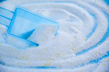 Mavi arka planda çamaşır tozu ile kepçeyi ölçmek