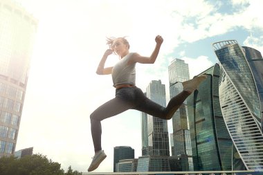 Fit vücut atlama ve çalışan genç kadın. Spor giyimde kadın model açık havada egzersiz yapıyor.