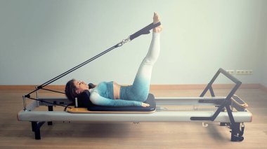Genç Asyalı kadın bir stüdyoda esneme sporu yapıyor.