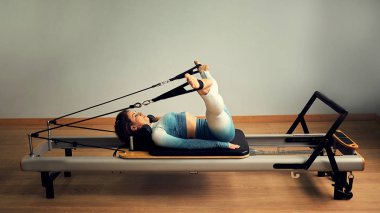 Genç Asyalı kadın bir stüdyoda esneme sporu yapıyor.