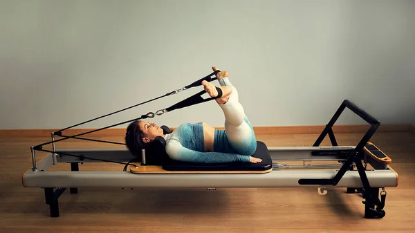 Mladá asijská žena pilates stretching sport v reformátor lůžko instruktor dívka ve studiu — Stock fotografie