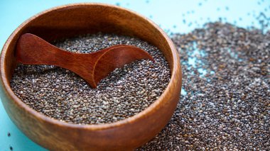 Mavi arka planda besleyici chia tohumları. kase chia tohumları ve mutfak masası üst görünümünde bir kaşık. Sağlıklı ve diyet superfood ürün.