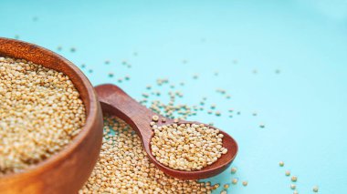 Mavi bir arka plan üzerinde beyaz Quinoa tohumları. Kase quinoa ve mutfak masası üst görünümünde bir kaşık. Sağlıklı ve diyet superfood ürün.