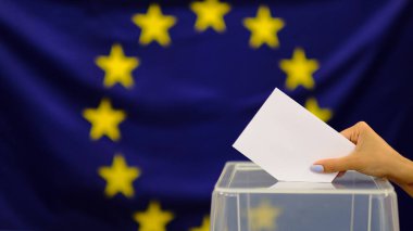 Seçim oylaması konsepti için oy pusulası tutuyor. Seçimler, kadının oyunu sandığa koyması. Avrupa Birliği bayraklarında.