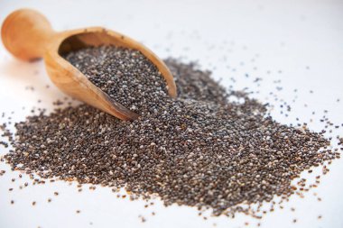 Beyaz bir arka plan üzerinde besleyici chia tohumları. kase chia tohumları ve mutfak masası üst görünümünde bir kaşık. Sağlıklı ve diyet superfood ürün.