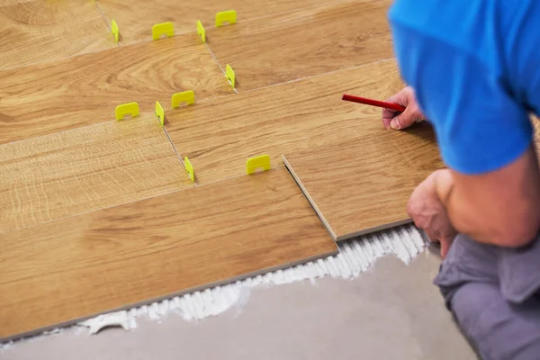 Close-up of handyman placing tile spacer. Placing the floor tiles. Home improvement — Stock Photo, Image