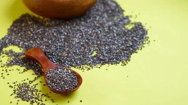 Voedzame Chia zaden op een gele achtergrond. Chia zaden in Bowl en een lepel op de keuken tafel bovenaanzicht. Gezond en dieet superfood product. — Stockfoto