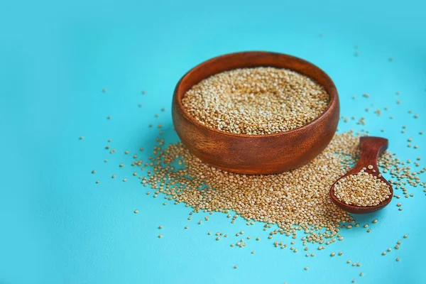 Białe nasiona quinoa na niebieskim tle. Quinoa w misce i łyżkę na stole kuchennym widoku z góry. Zdrowe i dietetyczne produkty Superfood. — Zdjęcie stockowe