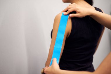 Yaralı kadın kolunda mavi bant ile kineziyoloji bandı tedavisi. Spor yaralanması kinesio tedavisi