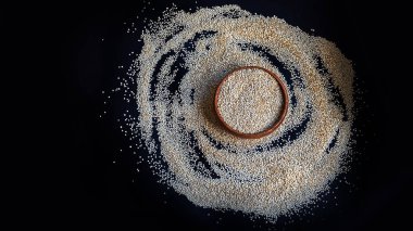 Siyah bir arka plan üzerinde beyaz Quinoa tohumları. Mutfak masası üst görünümünde kase quinoa. Sağlıklı ve diyet superfood ürün.