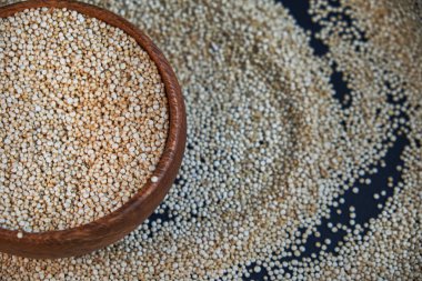 Siyah bir arka plan üzerinde beyaz Quinoa tohumları. Mutfak masası üst görünümünde kase quinoa. Sağlıklı ve diyet superfood ürün.
