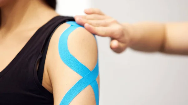 Tratamiento con cinta adhesiva cinesiológica con cinta azul en el brazo lesionado de la paciente. Lesiones deportivas tratamiento kinesio — Foto de Stock