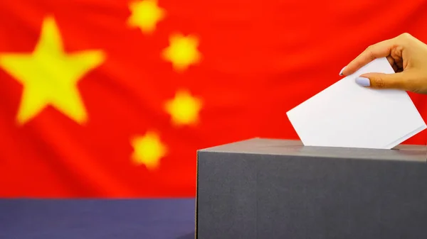 Ręczny papier do głosowania w głosowaniu wyborczym. wyborów, ręka kobiety oddanie jej głosu w polu głosowania. Flaga Chin na tle. — Zdjęcie stockowe
