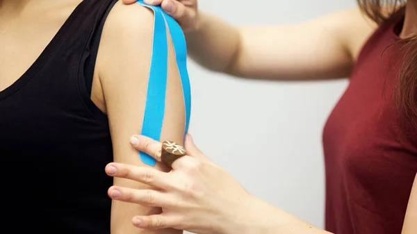 Kinesiologie tape behandeling met rode tape op vrouwelijke patiënt gewonde arm. Sport blessure kinesio behandeling — Stockfoto