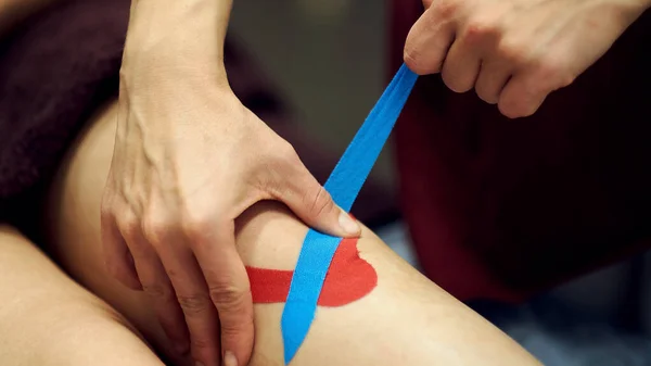 Traumatisme sportif traitement kinesio. thérapeute plaçant la bande de kinesio sur le genou des patients — Photo