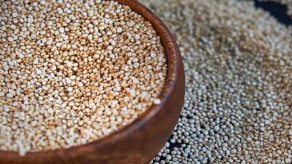 White quinoa seeds on a black background. quinoa in bowl on kitchen table top view. Healthy and diet superfood product. — Stock Photo, Image