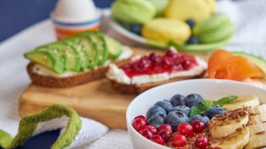 Kahvaltı üstü siyah arka plan. Böğürtlenli yulaf ezmesi, tahta tepside tost, fındık, kahve.