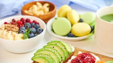 Kahvaltının üstü beyaz arka plan. Böğürtlenli yulaf ezmesi, tahta tepside tost, fındık, kahve.