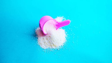 Çok renkli arka planda çamaşır tozu ile kepçeyi ölçmek