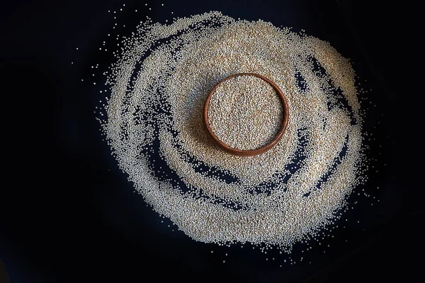 Białe nasiona quinoa na czarnym tle. Quinoa w misce na stole kuchennym widok z góry. Zdrowe i dietetyczne produkty Superfood. — Zdjęcie stockowe