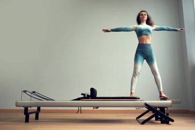 Leotard egzersiz pilates eğitimi. Atletik pilates yenilikçi egzersizleri. Pilates makinesi ekipmanı. Genç Asyalı kadın bir stüdyoda esneme sporu yapıyor.