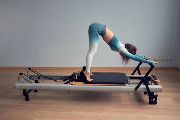 Trénink pilates v trikotu. Sportovní pilates reformační cvičení. Pilates strojní vybavení. mladá asijská žena pilates stretching sport v reformátor lůžko instruktor dívka ve studiu — Stock fotografie