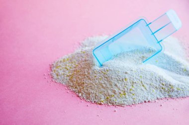 Çok renkli arka planda çamaşır tozu ile kepçeyi ölçmek