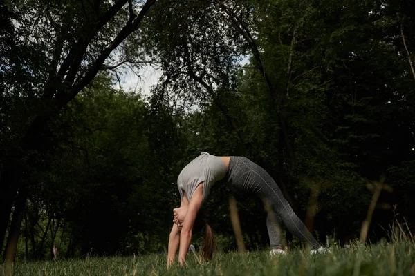 Photo of amazing young sports woman in park outdoors make sport stretching exercises. — Stock Photo, Image