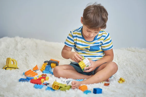 快乐的亚洲男孩在家里的白床上玩着五颜六色的建筑塑料块. — 图库照片