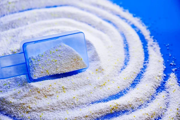 Measuring scoop with laundry powder on multi-colored background