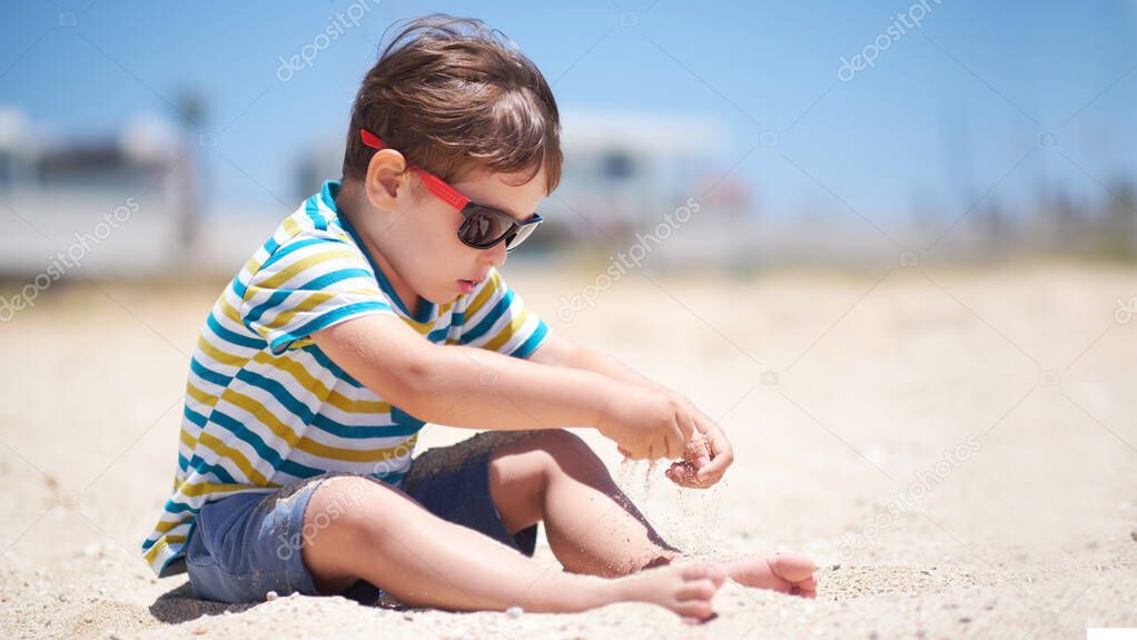 holiday, little boy three years old fun digging in the sand at the beach