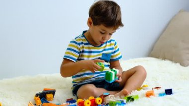 evde beyaz Yatak üzerinde renkli inşaat plastik bloklar ile oynarken yavaş hareket asya çocuk .
