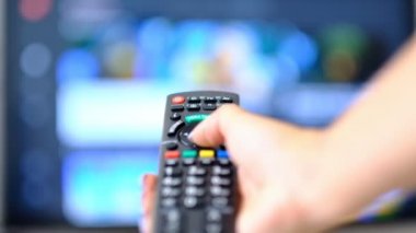 yavaş çekim kadın Tv izler ve uzaktan kumanda üzerinde bir düğmeye basar. el Tv uzaktan kumandatutarak ve akıllı tv kapatın. Kanal sörfü. bulanık arka plan