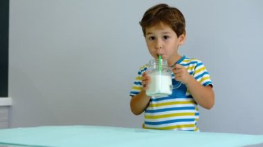 yavaş hareket asya Sevimli küçük çocuk mutfakta süt içme. neşeli çocuk milkshake içmek için seviyor