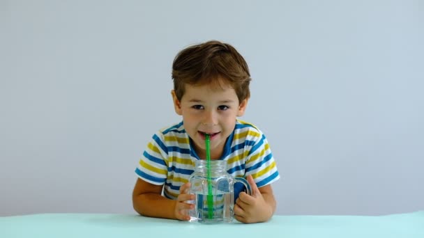 Cámara lenta asiático lindo niño bebiendo agua en cocina. alegre chico le gusta soplar burbujas — Vídeos de Stock