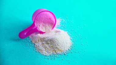 Çok renkli arka planda çamaşır tozu ile kepçeyi ölçmek