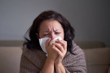 Hasta bir kadın burun sümkürürken soğuk algınlığına yakalandı. Kanepeye oturdu, boğazı ağrıdı, boğazı ağardı ve evde aspirin içti. Saman nezlesi konsepti.