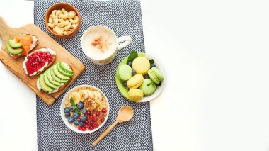 Kahvaltı manzarası beyaz arkaplanı izole ediyor. Böğürtlenli yulaf ezmesi, tahta tepside tost, fındık, kahve.