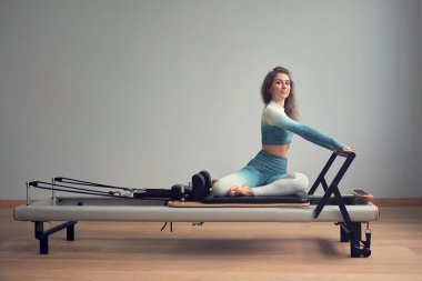 Leotard egzersiz pilates eğitimi. Atletik pilates yenilikçi egzersizleri. Pilates makinesi ekipmanı. Genç Asyalı kadın bir stüdyoda esneme sporu yapıyor.
