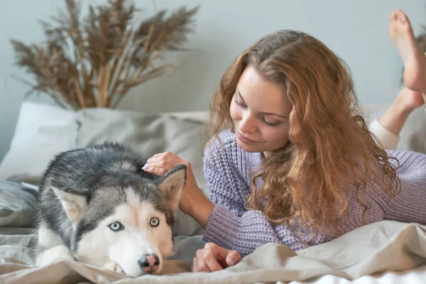 Рыжая женщина отдыхает дома со своей собакой Хаски — стоковое фото